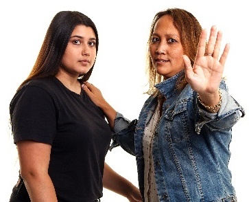 A woman with her hand on another woman's shoulder, and her other hand up in a 'stop' gesture.