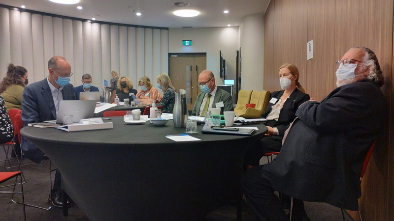 Masked attendees sit at round tables