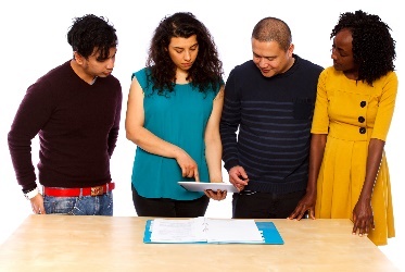 A group of four people looking at a document together at a table. 