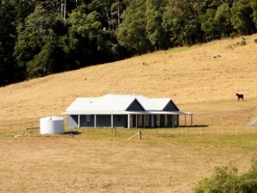 A farm house beside a paddock.