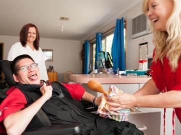A support worker helping a man in a wheelchair in his home.