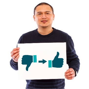 A person holding up a sign. On the sign is an arrow pointing from a thumbs down to a thumbs up.