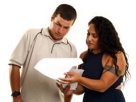 A woman is helping a man read a document.